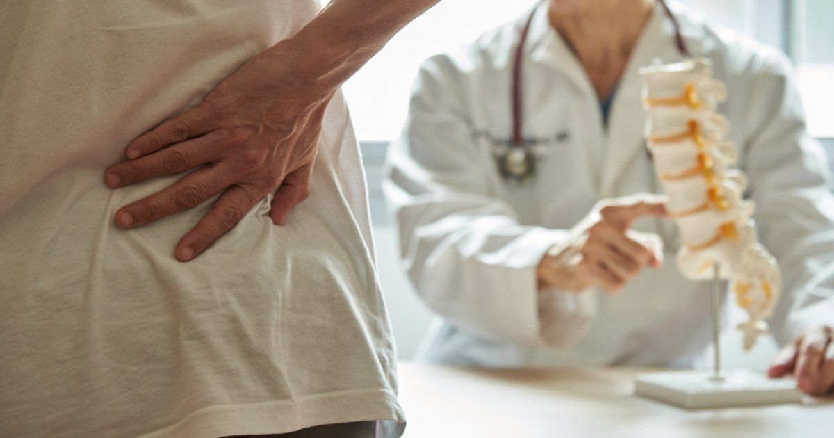 patient holding back-doctor showing spine model 